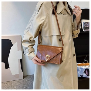 Detail of cognac patent leather crossbody bag with golden water-drop twist lock clasp
