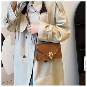 Detailed view of brown patent leather bag with a gold teardrop-shaped twist lock