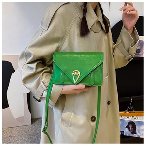 Detail view of bright green patent leather crossbody bag with golden teardrop lock