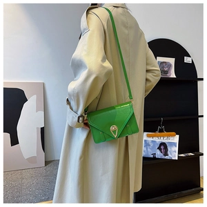 Detail of bright green patent leather crossbody bag with water drop lock on beige coat