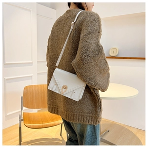 White minimalist envelope crossbody bag featuring a golden triangular metal lock and stitching