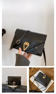 Detail of black patent leather crossbody bag featuring a unique gold teardrop lock