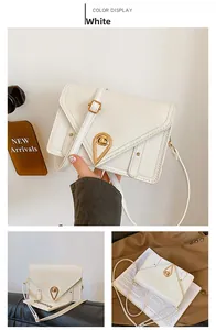Detail view of white leather shoulder bag featuring gold triangle lock and strap stitching