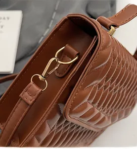 Gedetailleerde close-up van bruine gewatteerde leren tas met glanzende goudkleurige hardware