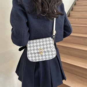 Elegant houndstooth wool saddle bag with gold horseshoe buckle worn on a shoulder