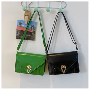 Detail of green and black patent leather crossbody bags with gold teardrop locks