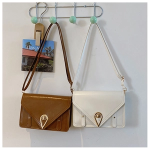 Detail view of brown and white crossbody bags with teardrop locks hanging on a wall