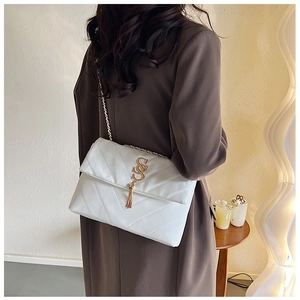 Sac bandoulière blanc matelassé avec boucle dorée en S et chaîne sur manteau marron