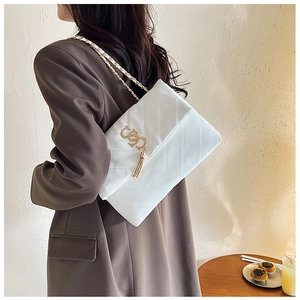 Détail d'un sac bandoulière blanc matelassé avec chaîne dorée et gland décoratif