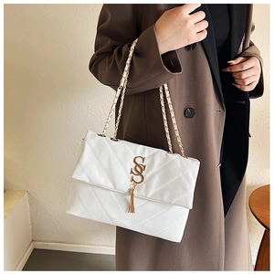 Détail du sac blanc en similicuir matelassé avec chaîne dorée et pompon métallique