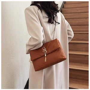 Détail d'un sac cabas en cuir matelassé marron avec finitions dorées et pompon métallique