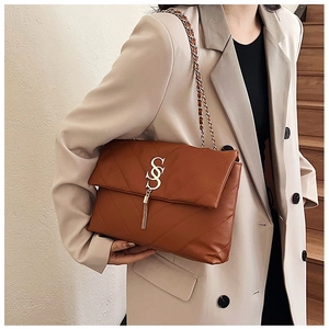 Détail du sac à bandoulière en cuir marron matelassé avec chaîne et pompon dorés