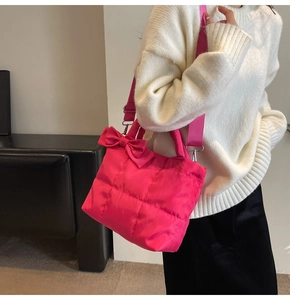 Detailed view of magenta quilted tote bag with large bow and wide shoulder strap