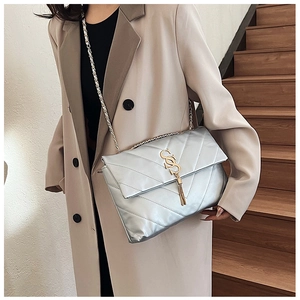 Détail d'un sac en cuir matelassé argenté avec logo S doré et pompon à franges chic