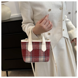 Detail of red and grey tweed mini bucket bag with leather strap on a cream tweed outfit