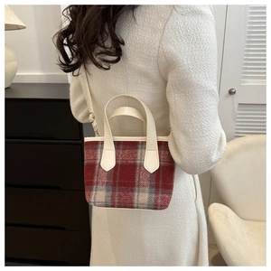 Detail of red and grey wool check handbag with white leather strap shown on a model