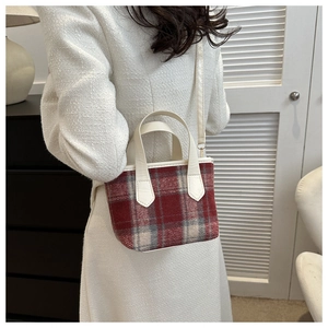 Detail of red plaid wool mini bag with cream leather strap on woman in beige coat
