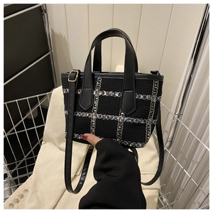 Detail of a black tweed handbag with blue and white checks held in a metal basket