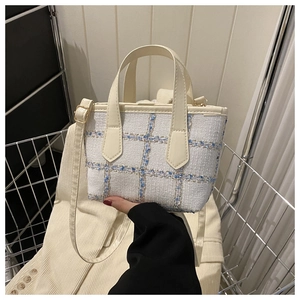 Close-up of white and blue tweed handbag with gold metallic thread and leather handle