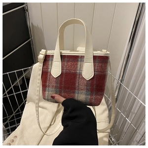 Detail of vintage red and grey plaid wool handbag with cream leather strap and gold buckle