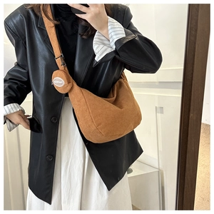Detail of caramel corduroy crescent bag featuring a round detachable coin purse charm