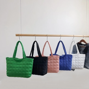 Quilted nylon tote bags in green, black, pink, blue and white on a wooden display hanger
