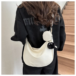 Detail of off-white nylon dumpling bag with wide strap and plush charcoal charm