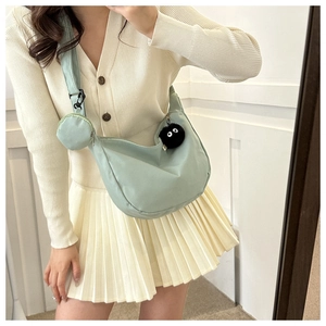 Detail of light green nylon crescent bag with mini coin purse and coal sprite charm