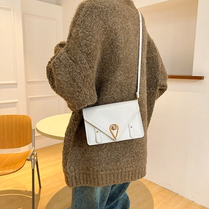 Chic white leather crossbody bag with golden water-drop lock and V-flap design on a model