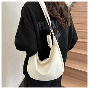 Detail view of a cream-white crescent nylon bag with a small round coin purse attachment