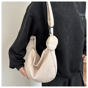 Detail of off-white corduroy crescent bag and round coin purse on a wide shoulder strap