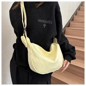 Detail of light yellow nylon crescent bag with wide strap and small round coin purse