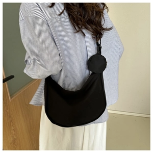 Close-up of black nylon crescent bag with adjustable strap and detachable round coin purse