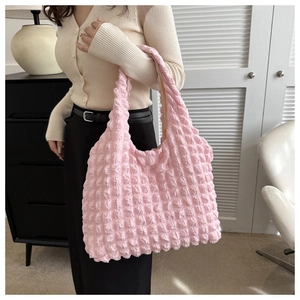 Sac à main rose pâle en tissu texturé à bulles porté par un mannequin féminin en intérieur