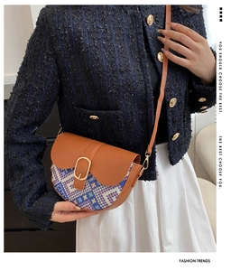 Close-up of bohemian woven crossbody saddle bag with leather flap and golden buckle