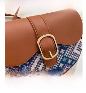 Detailed close-up of ethnic style saddle bag with colorful geometric patterns and gold buckle
