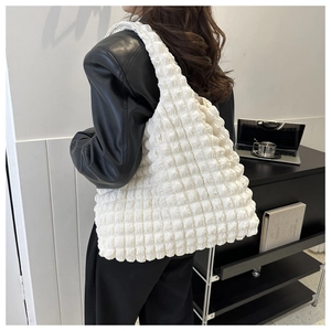 Vue détaillée du tissu blanc à texture gaufrée sur un sac à bandoulière léger et chic
