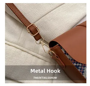 Detail of golden hardware hook and adjustable strap on a patchwork ethnic saddle bag