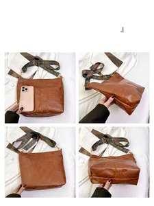 Brown leather tote bag showing wide woven strap and size comparison with phone