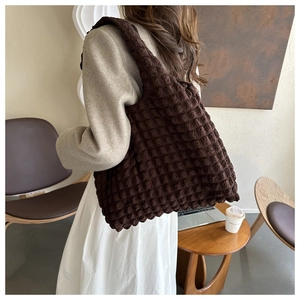 Détail du sac cabas marron foncé à texture bulles 3D porté par un mannequin