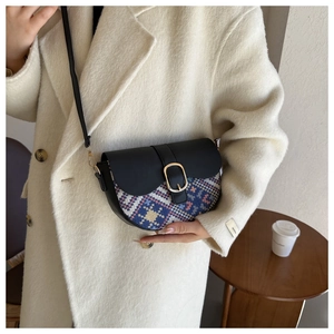 Ethnic style saddle bag with geometric weaving and gold buckle worn on white coat