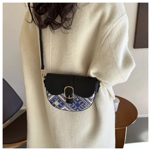 Detailed shot of a vintage saddle bag with ethnic weaving on a white wool coat