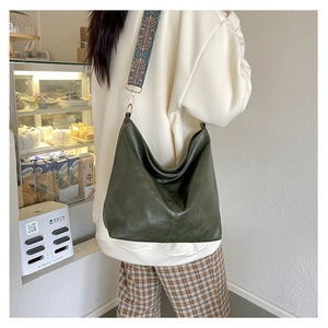 Detail of dark green hobo bag featuring a wide ethnic style patterned fabric strap