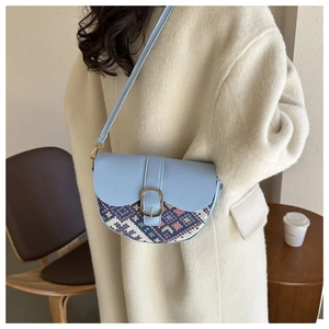 Detail of light blue saddle bag with ethnic weave pattern on white coat