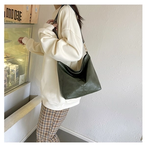 Detail of dark green leather shoulder bag with vintage patterned strap and gold hardware