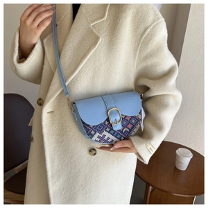 Light blue saddle bag featuring ethnic embroidery and golden buckle on cream coat
