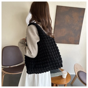 Détail d'un sac cabas noir matelassé à bulles dans un cadre de vie chaleureux