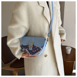 Detail of light blue saddle bag with ethnic pattern flap and golden buckle on model