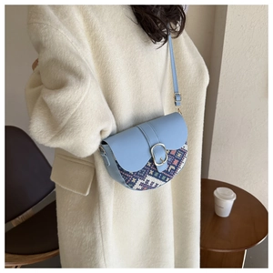 Close-up of sky blue saddle bag with ethnic geometric weave pattern on a white coat