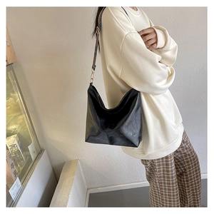 Close-up of black glossy leather tote bag featuring a floral patterned shoulder strap